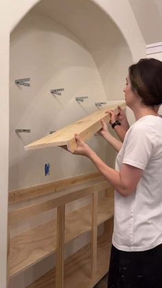 a woman standing in front of a shelf holding a surfboard on it's side