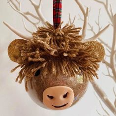 an ornament shaped like a cow with hair on it's head hanging from a tree