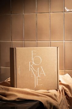 an open book sitting on top of a table next to a brown tile wall with white lettering