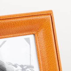 an orange leather frame holds a black and white photo