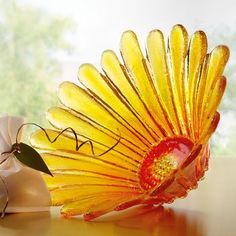 a yellow flower sitting on top of a table next to a vase with flowers in it