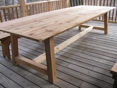 a wooden table sitting on top of a wooden deck next to two benches and railings