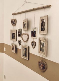 a group of pictures hanging on the wall next to a wooden stick with hearts attached