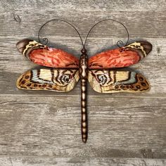 an orange and black butterfly sitting on top of a wooden floor