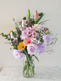 a vase filled with lots of different colored flowers