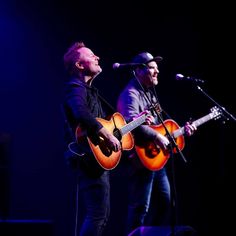 two men are playing guitars on stage