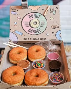 an open box with donuts and toppings in it on a table next to other items