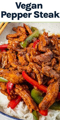 a plate full of meat and peppers on rice with chopsticks in the background