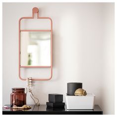 a table with a mirror, candle and other items on it in front of a white wall