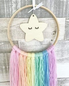 a wooden star hanging from a hoop with multicolored yarn