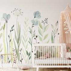 a white crib in front of a painted wall with flowers and plants on it