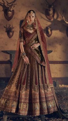 a woman in a brown and gold bridal gown with deer heads on the wall behind her