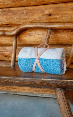 a blue and white blanket sitting on top of a wooden bench next to a log wall