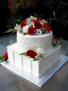 a wedding cake with red and white flowers on top