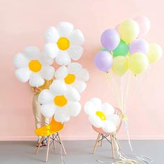 a person standing in front of balloons and chairs with flowers on the chair, holding them up