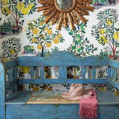 a blue bench with a hat on it in front of a wallpapered room