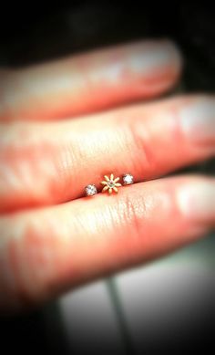 a person's hand holding a tiny ring with two small flowers on it,