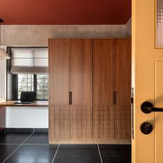 an open door leading to a room with wooden cabinets and black tile flooring on the walls