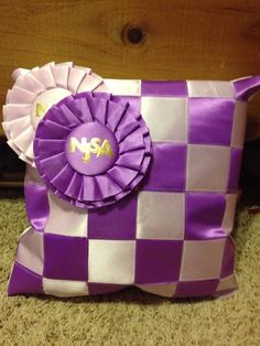 a purple and white checkered pillow with a large rosette on the front side