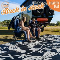 two people sitting on chairs in front of a camper with the words back in stock