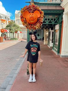 a woman standing in front of a building with a pumpkin head on it's head