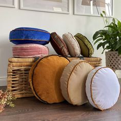 several round pillows stacked on top of each other in front of a potted plant