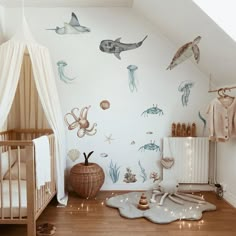 a baby's room with an ocean theme on the wall and wooden flooring