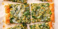 several slices of pizza with cheese and spinach on them sitting on a piece of parchment paper