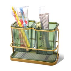 three toothbrushes and two toothpaste in a metal holder on a white background