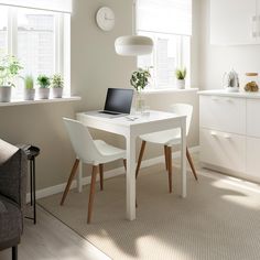 a white table with two chairs and a laptop on it in front of a window