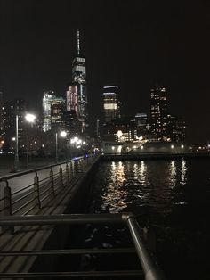 the city skyline is lit up at night with lights reflecting on the water and buildings in the background