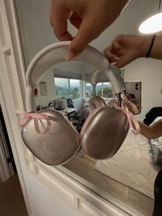 a pair of bras is being held up in front of a mirror with pink ribbon