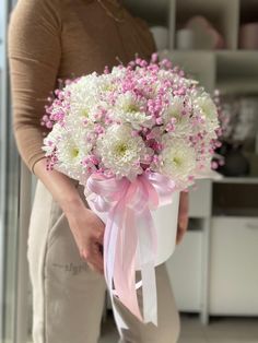 a woman holding a bouquet of white and pink flowers