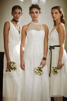 three women in white dresses standing next to each other with flowers on their bouquets