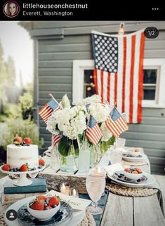 a table topped with cake and flowers on top of a wooden table next to an american flag