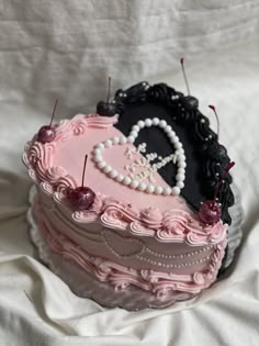 a pink and black heart shaped cake with pins sticking out of it's sides