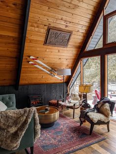 a living room with wood paneling and large windows on the ceiling is filled with furniture