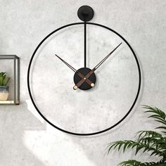 a clock is hanging on the wall next to a potted plant in a vase