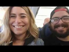 a man and woman are smiling for the camera while sitting on a bus together in front of some people