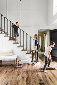 two children are playing on the floor in front of stairs, while another child is walking up