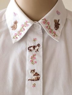 a close up of a person wearing a white shirt with cats and flowers on it