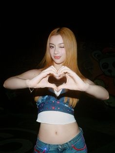 a woman making a heart with her hands in the shape of a heart on top of her stomach