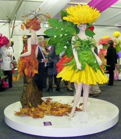 two mannequins dressed as flowers and leaves on display at an art show