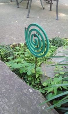 a green sculpture sitting in the middle of a garden next to some tables and chairs