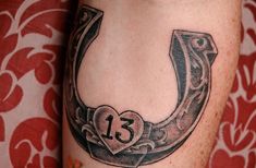 a horseshoe tattoo with the number thirteen in it's center and a heart at the bottom