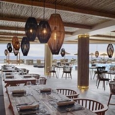 an empty restaurant with tables and chairs, lights hanging from the ceiling and large windows