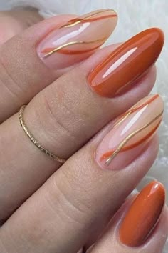 an orange manicure with gold lines on it