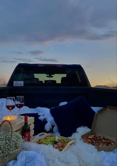 a truck bed with food and wine in the bed, next to it is a blanket