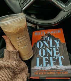 there is a book, drink and glove on the car floor next to the steering wheel