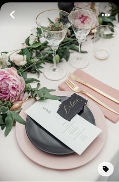 the table is set with pink flowers and place cards for guests to write their names